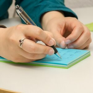 a person writing on a notepad with a pen